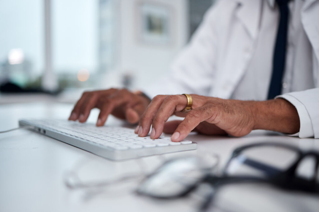 doctor typing on a keyboard in an EHR practice management software