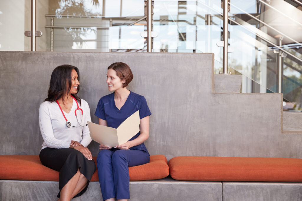 two female healthcare workers discussing a health records (EHR)